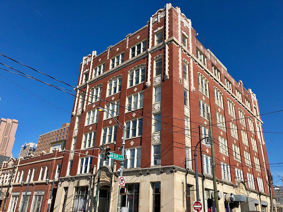 The Odd Fellows Building at the corner of Auburn Avenue and Bell Street, six storeys of red brick with white terracotta trim over a stone ground floor, telephone wires crossing the front of it.