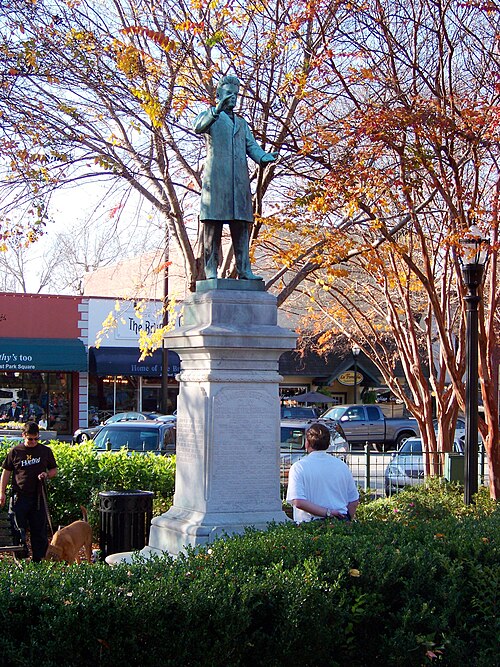 A bronze statue of Georgia senator Alexander S. Clay in the park, storefronts across the street behind it.