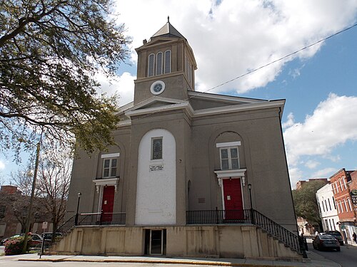 First African Baptist Church's gray stucco Greek Revival facade, a domed bell tower over the entrance and paired red doors under arched windows.