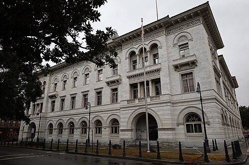 The white marble Tomochichi federal building, a Beaux Arts facade of round arched windows and balconies rising three storeys above an arcaded ground floor.
