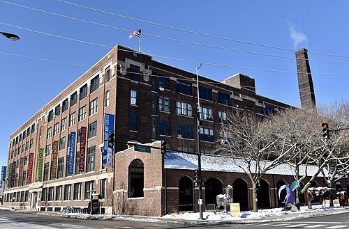 A five storey brick warehouse at 35th and Racine, arched openings along the ground floor and a tall brick smokestack behind it.