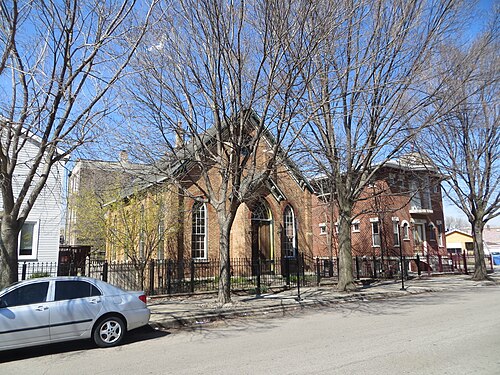 A peaked brick building behind bare trees on Racine Avenue near 31st Street, parked cars along the curb.