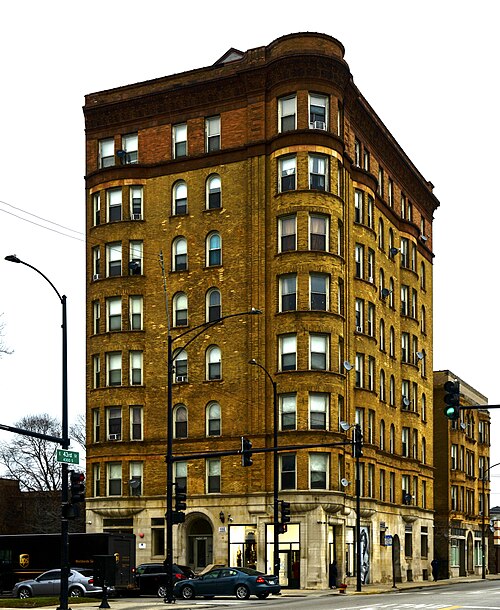 Belmonte Flats, a seven storey yellow brick corner apartment building with a rounded bay corner above a limestone storefront base.