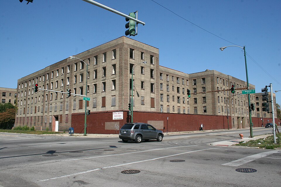 The Rosenwald Courts complex at 47th Street and Wabash Avenue, photographed in 2012 while vacant, brick walls boarded at every window and a red painted ground floor along the sidewalk.