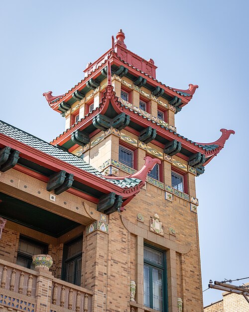 The Pui Tak Center's brick tower, twin green tile pagoda roofs and red wooden brackets framing the upper windows.