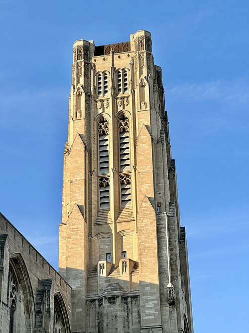 Rockefeller Chapel's bell tower in close up, limestone piers and pointed arches climbing to louvered openings at the top.