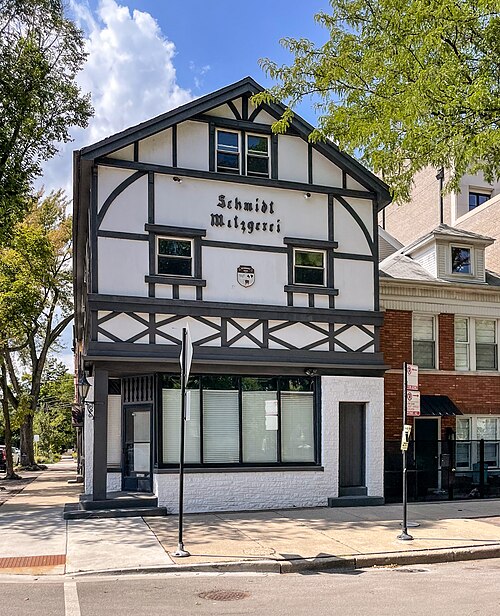 A half timbered building at Hudson and Menomonee, white stucco between dark wood framing, the old Schmidt Mitzgerei lettering still across the gable.