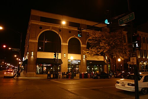The corner of North Avenue and Wells Street at night, arched brick windows over ground floor shops.