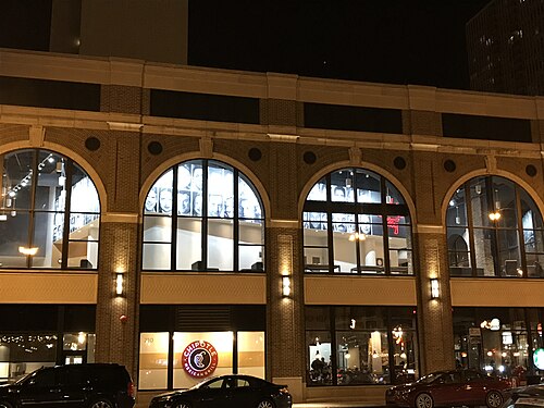 Arched brick windows on the building that houses Second City on Wells Street, framed photographs lit in the windows above a street level restaurant.