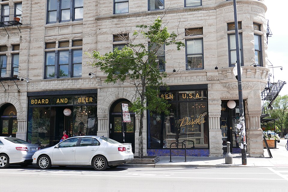 The limestone corner of the Thalia Hall building on 18th Street at Allport Street, arched storefront bays and a corner turret above street level.
