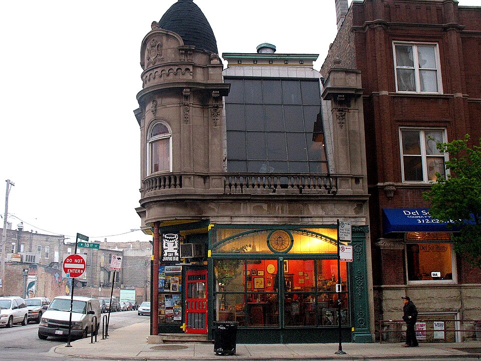 Cafe Jumping Bean's domed corner turret at 18th Street and Bishop Street, green painted storefront ironwork and a red door under a stone bay window.