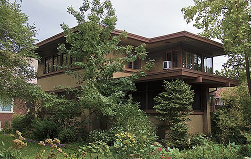 The Allan Miller House on Paxton Avenue, a Prairie style house with deep cantilevered eaves and dark wood trim, set behind dense landscaping.