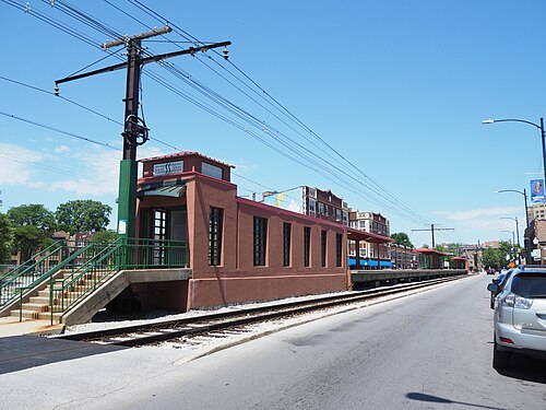 The South Shore Metra Electric station, a low brick platform building beside tracks running at street level down the middle of the road.