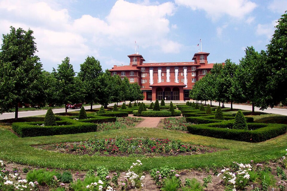 The South Shore Cultural Center's clubhouse across its formal garden, a symmetrical red brick and terracotta facade with twin corner towers.