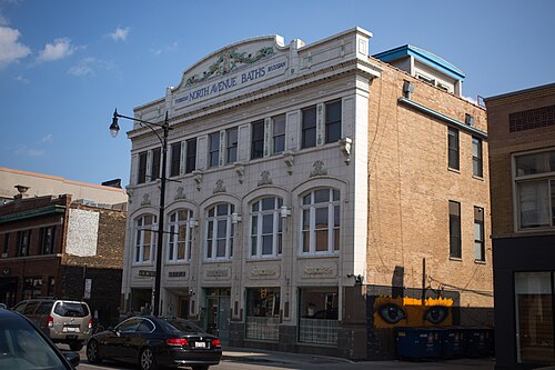 The cream terra cotta facade of the old North Avenue bath house, arched windows and ornament above a storefront.