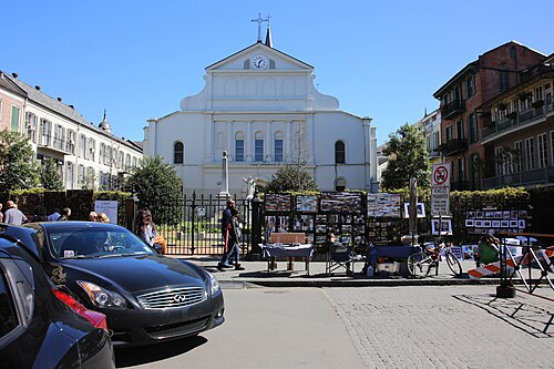 The back of St. Louis Cathedral from Royal Street, across the walled garden. Artists' work hangs along the iron fence and a sign keeps vehicles off the block for most of the day.