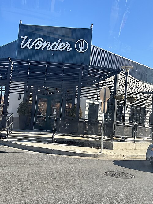 A dark corrugated metal food hall building at Canton Crossing, a white Wonder sign over the entrance and owl statues on the roofline.