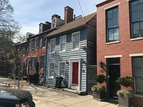 A wood-frame house with a blue clapboard front on Montgomery Street, brick rowhouses standing on either side of it.