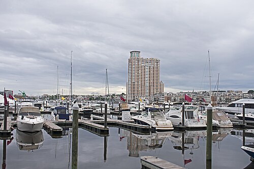 The HarborView tower on Key Highway seen across the water from Harbor East, a high rise condominium building above a marina of moored boats.