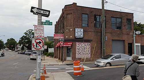 A two storey brick commercial building with liquor store signage at a Falls Road intersection.