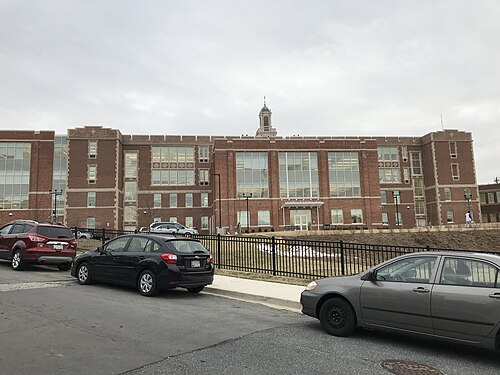 A large three storey red brick school building with a central cupola, at the west end of the Avenue.