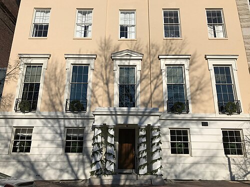 The Mount Vernon Club's cream painted three storey facade at 8 West Mount Vernon Place, doric columns framing the entrance and symmetrical windows above.