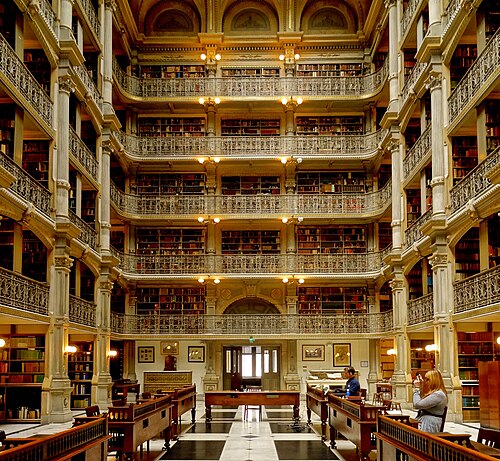 The George Peabody Library reading room, five stacked tiers of wrought iron book balconies rising to a skylight.