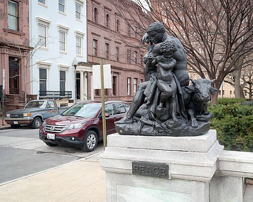Barye's bronze group Peace on its plinth in the park, brownstone and painted townhouse facades across the square behind it.