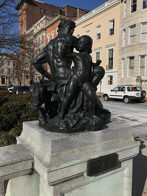 Barye's bronze group War on its stone plinth in the west park, townhouses behind.