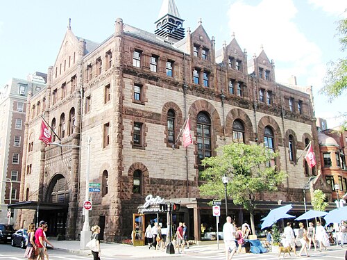 A Romanesque corner building in red sandstone and brownstone, arched windows over ground floor storefronts and a corner tower, at Exeter and Newbury Streets.