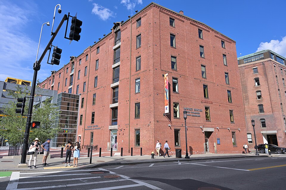 The Boston Children's Museum's Yawkey Center, a six storey red brick warehouse at Congress Street with its sign and banner over the entrance, pedestrians at the corner crosswalk.