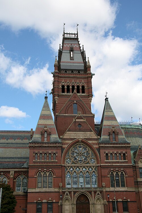 The Gothic Revival brick tower of Memorial Hall, banded in red, cream and grey slate, with a rose window and steep corner turrets against the sky.