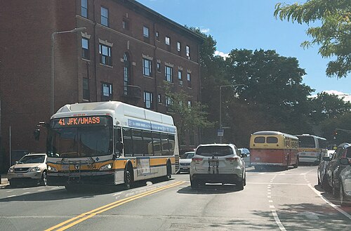 A number 41 bus stopped in traffic on Centre Street, a four storey brick apartment building behind it.