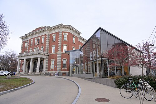 Curtis Hall's red brick facade with a columned portico, joined by a glass walled library wing with bicycles parked out front.