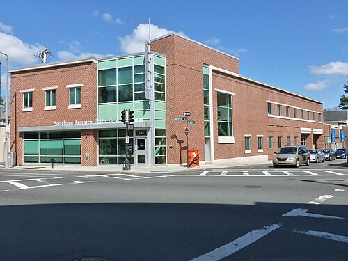 The brick corner of the Southern Jamaica Plain Health Center at Centre and Green Streets, green glass panels wrapping the second floor.