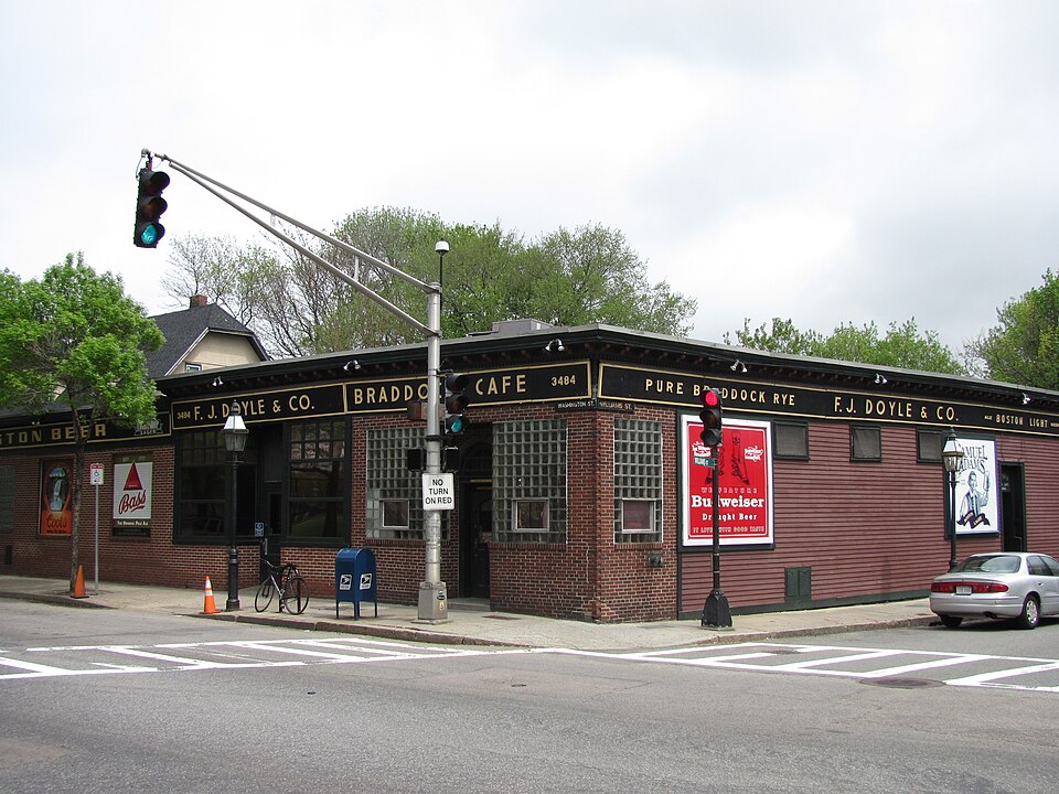The corner of Washington and Williams Streets, F. J. Doyle and Co.'s Braddock Cafe in red brick with black and gold signage, a traffic light overhead.