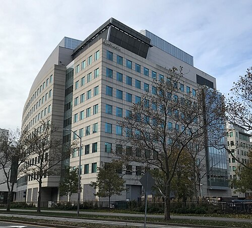 A curved stone and glass laboratory building with the Novartis name mounted near the roofline, bare trees in front.