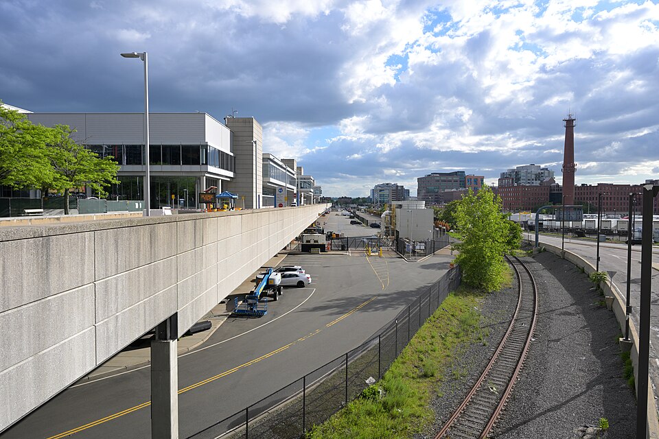 The convention center's east side above a service road, a single freight rail track curving alongside it under a cloudy sky. The casino scene was built inside an exhibition hall, not on this side of the building.