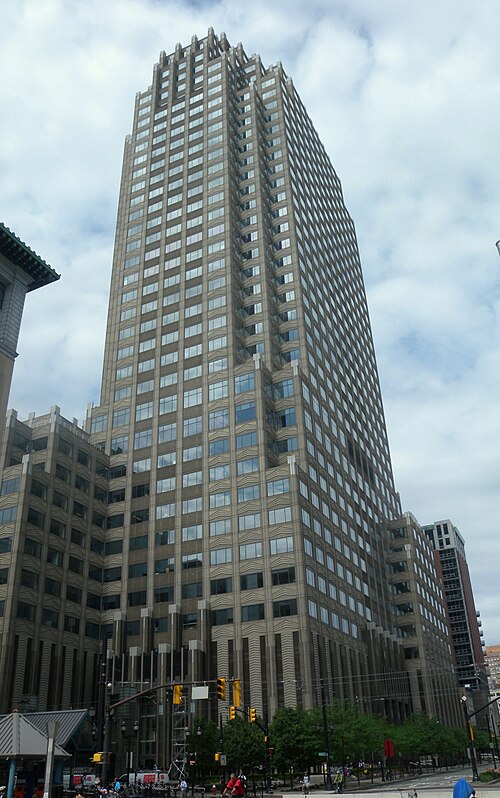 101 Hudson Street's stepped, pale stone crown against the sky, traffic signals and trees at its base.