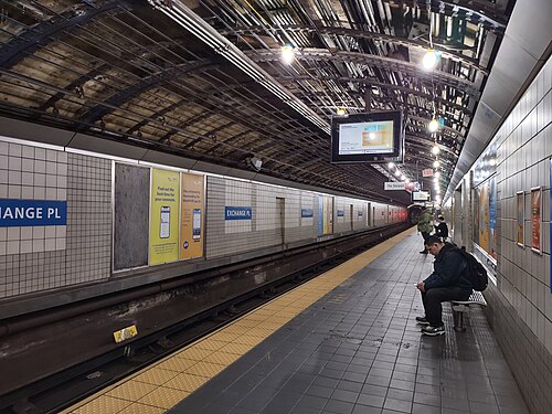 The underground PATH platform at Exchange Place, tiled walls and an arched ceiling, a train approaching along a platform marked Exchange Pl.