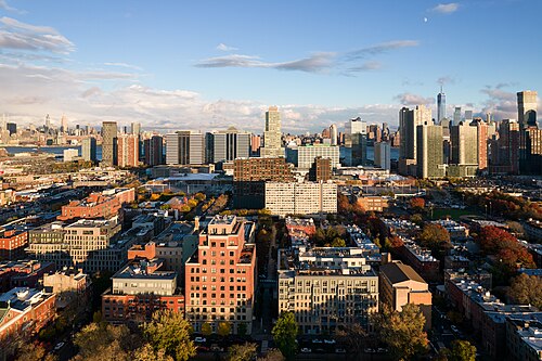 An elevated view over the residential blocks around the park, brick buildings leading toward the distant skyline.