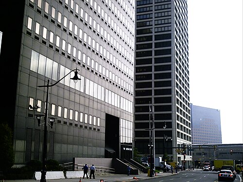 Glass and steel office towers meeting at a street corner, a cast iron lamppost in the foreground.