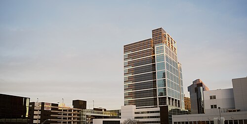 A glass walled office tower catching late sun above a parking garage.