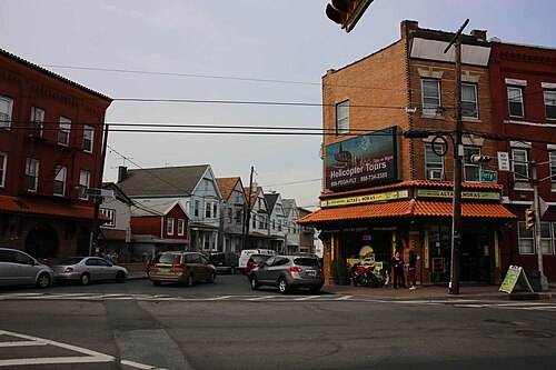 A corner building with an orange tiled mansard roof over a snack counter, a travel agency sign reading Helicopter Tours above.