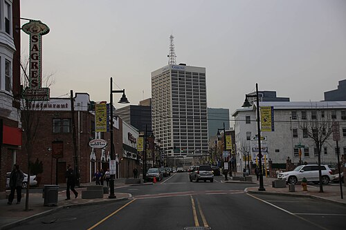 Ferry Street looking west toward downtown Newark's high rises, past restaurant signs and hanging street banners.