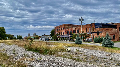 A brick industrial building beside a gravel lot on Republic Street, with grain elevators visible down the street.