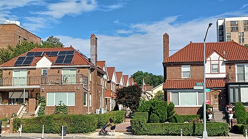 Brick houses on Narrows Avenue with red tile roofs and clipped hedges, and a narrow lane running back between two of them.