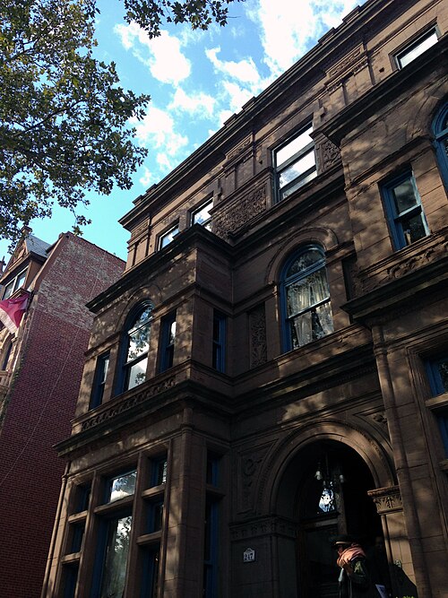 The John C. Kelley Mansion at 247 Hancock Street from the sidewalk, a brownstone front with carved panels between the floors and an arched entrance with a lantern inside it.