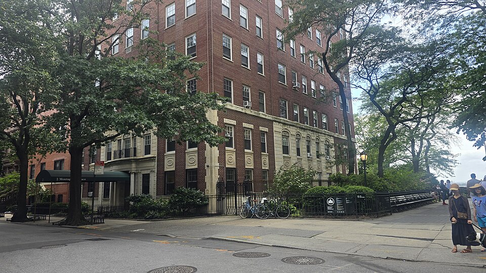 The top of Montague Terrace where it meets Montague Street, with the awning of number 2 under the trees and the Promenade benches beyond the railing on the right.