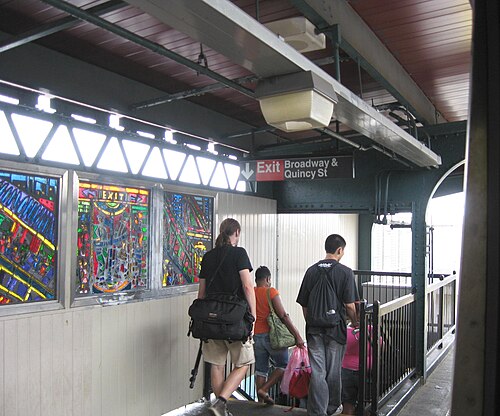 The northbound platform at Gates Avenue on the BMT Jamaica Line, looking west on a rainy midday.
